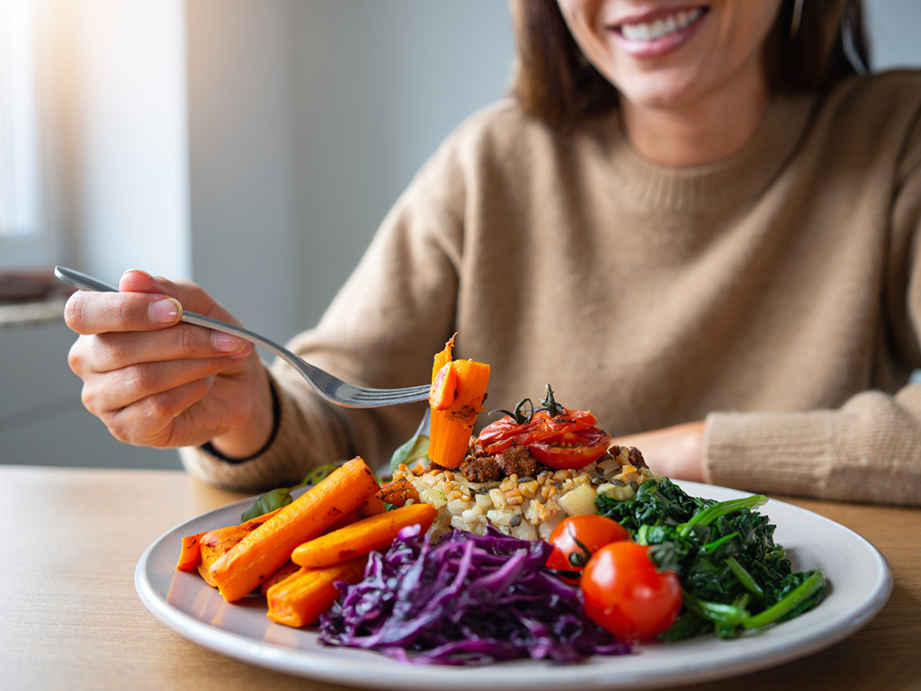Kvinna som äter en färgglad vegansk måltid